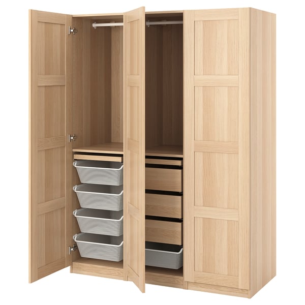 A wooden PAX wardrobe in white stain, featuring open doors revealing drawers, shelves, and baskets inside.