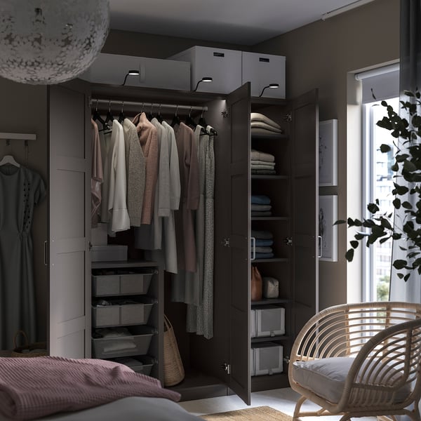 Modern bedroom with dark PAX wardrobe and wicker chair.