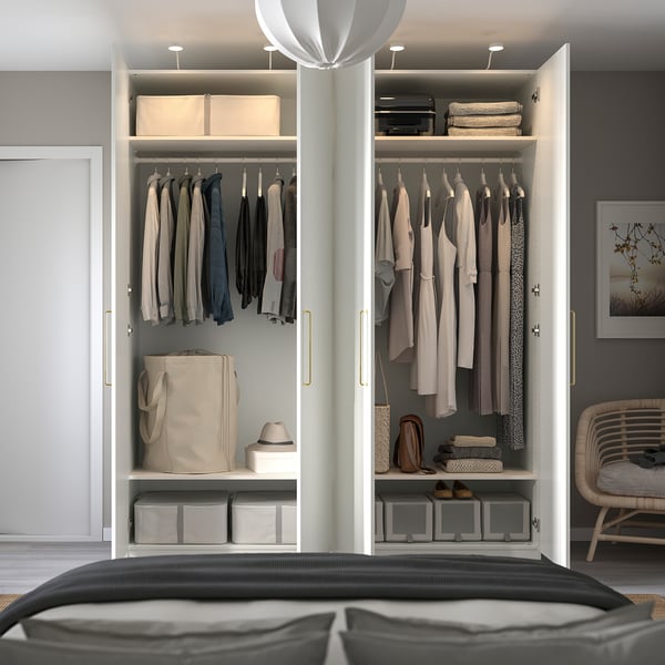Modern open wardrobe with clothes, bags, hats, and storage boxes on shelves; integrated lighting.