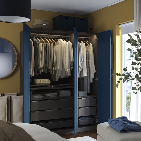 Open navy blue PAX wardrobe showing clothes, drawers with organisers, and mesh basket.