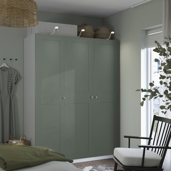 Teal PAX wardrobe between window & bed, with pendant light, baskets, chair, and plant.