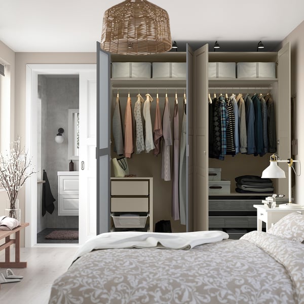 Modern bedroom with open closet showing clothes, drawers, and shelves inside.