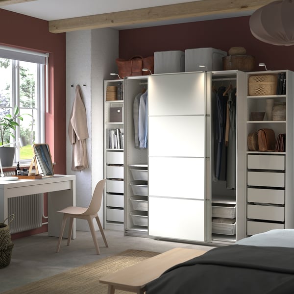 Modern bedroom with white PAX wardrobe, sliding doors, clothes, and storage shelves.