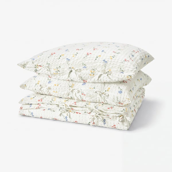 Four white pillows with colourful floral patterns neatly stacked; soft, breathable cotton/viscose fabric; seersucker texture.