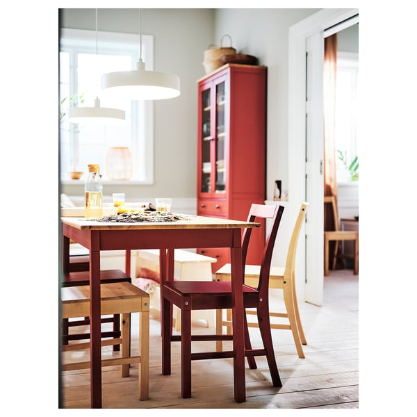Simple dining setup with wooden table, red PINNTORP chairs, and hanging lamp.