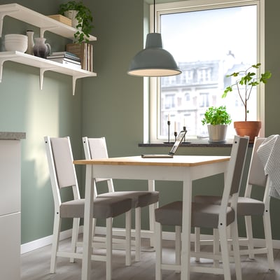 Small cosy dining setup with white table and grey chairs, decorated with green plants, under a blue pendant light.