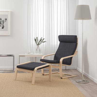 Minimalist living space with blue POÄNG armchair, matching footstool, lamp, and plant. Light walls and beige rug create a cosy atmosphere.