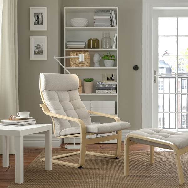 Grey POÄNG armchair with footstool, bookcase, and city view.