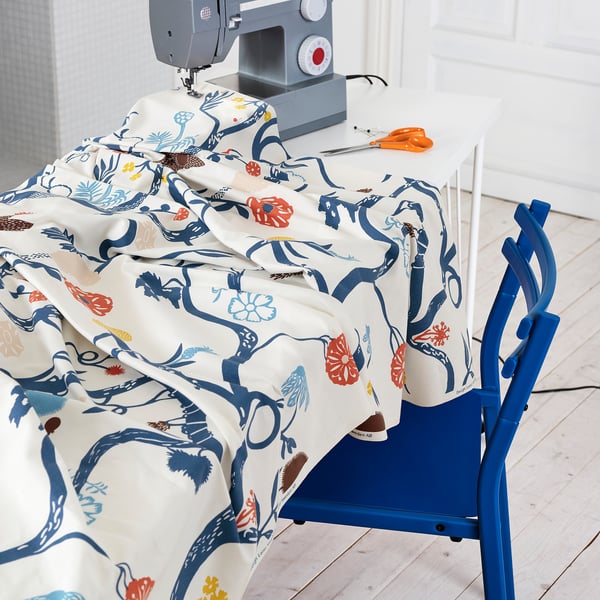 A sewing machine on a table with colourful, patterned fabric draped over it, ready for crafting.