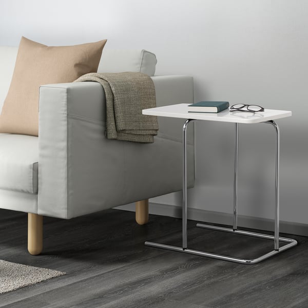 Modern living room showing a grey sofa with a side table next to it. The table has a book and glasses on top.