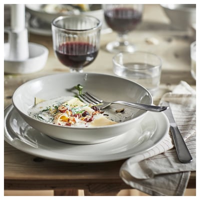 A plate of food with a glass of wine and fork on a wooden table.