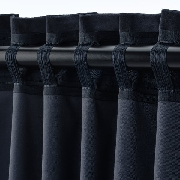 Close-up of black velvet curtains with rod pocket header. Multiple pleats hang neatly, showing room-darkening fabric.