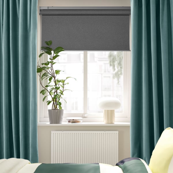 Modern room with dark grey-turquoise SANELA curtains, plant, lamp, and radiator.