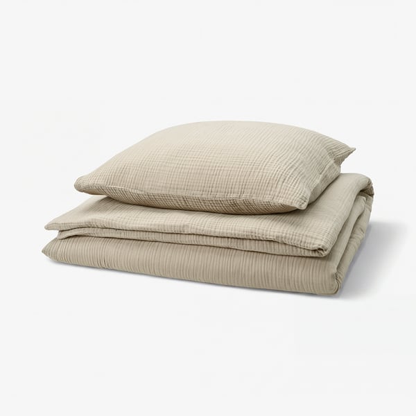 Stacked beige bed linens with wavy texture, made of 100% cotton.