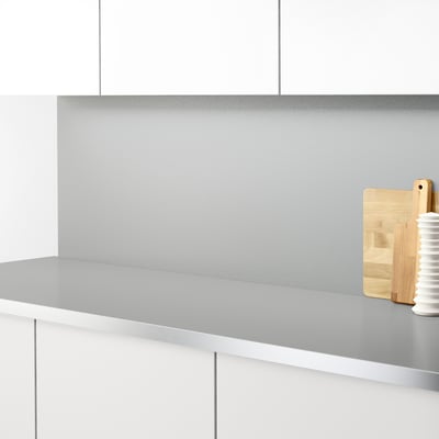 Modern kitchen with stainless steel counter & backsplash, wooden cutting board, and white vase.