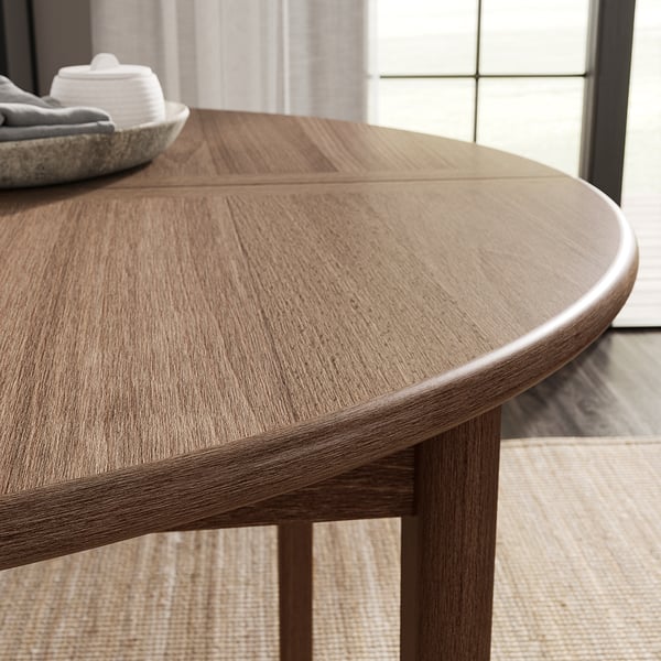 Round, wooden dining table with smooth edges, featuring natural brown stain.