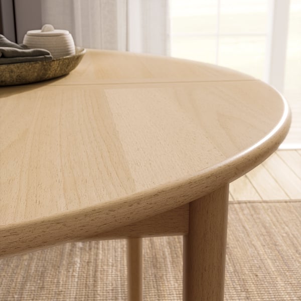 Light wooden round dining table with smooth edges and light flooring. Simple, modern design.