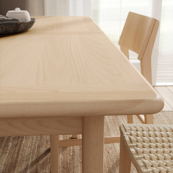 Light wooden dining table with chairs, light-colored, rectangular, modern minimalist design.