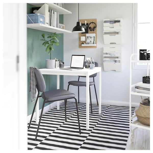 Modern office with SKURUP lamp, sleek desk, grey chair, and striped rug.