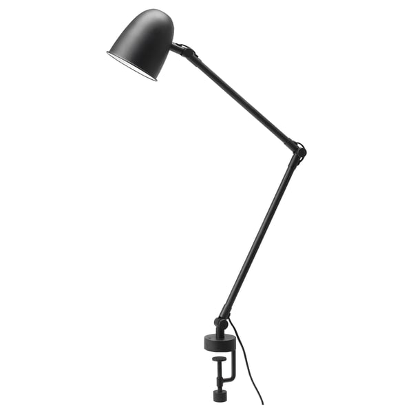 A black SKURUP lamp with an adjustable arm and shade, designed for versatile use as both a desk and wall lamp.
