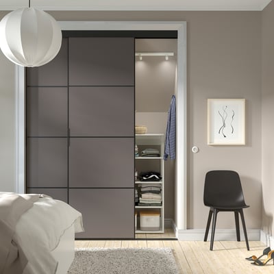 Modern bedroom with SKYTTA sliding closet doors, black chair, minimalist decor.
