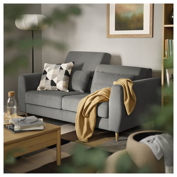 Modern grey sofa with geometric pillows, cosy throw, and stylish floor lamp in an inviting living space.