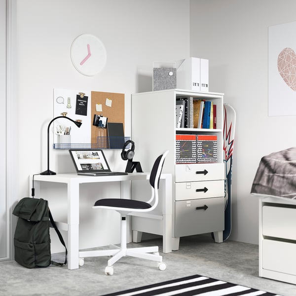 Small white study area with grey chair, desk, bookshelf, and green bag; modern minimalist design.