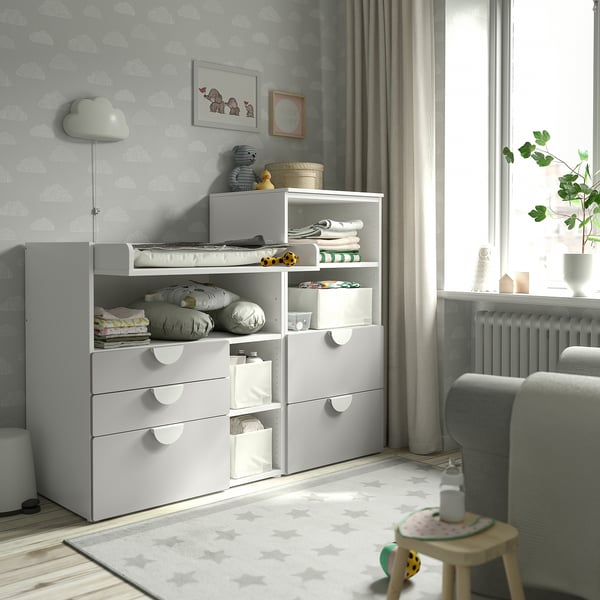SMÅSTAD changing table & storage in nursery. Light grey, white, multi-shelf & drawer units. Cloud wallpaper, grey chair, toy, plant.
