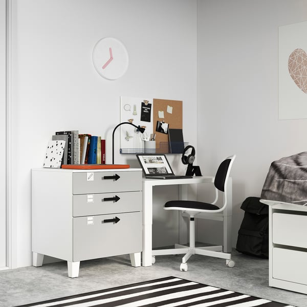 Minimalist kids study area with white SMÅSTAD desk and chair, books, laptop, and wall clock.