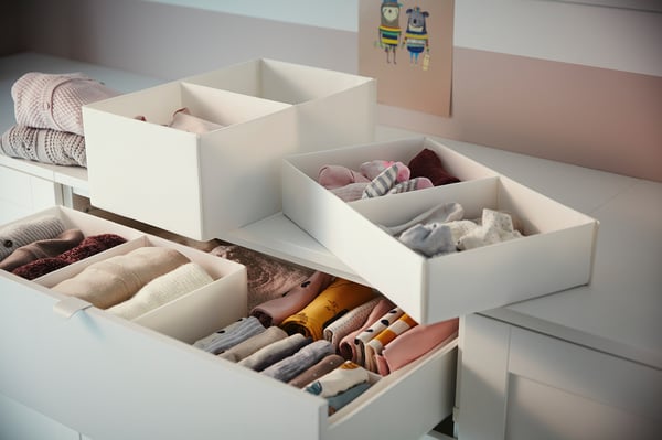 White SMÅSTAD drawers with baby clothes, small compartments for socks, larger items in bottom drawers.