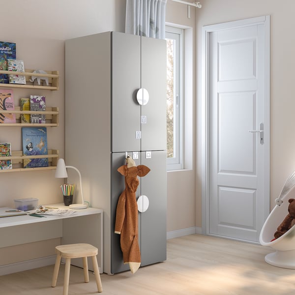 Kids grey storage unit with shelves, hanging area, and hooks in a room with a desk and books.