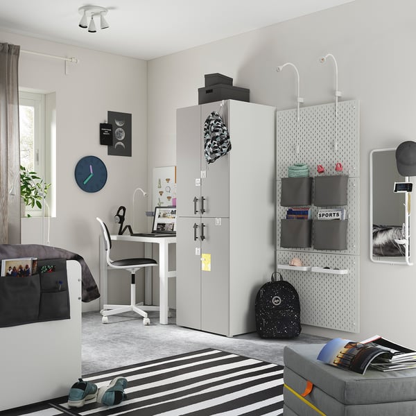 Teen bedroom with grey SMÅSTAD wardrobe, black backpack, striped rug, and desk with chair.