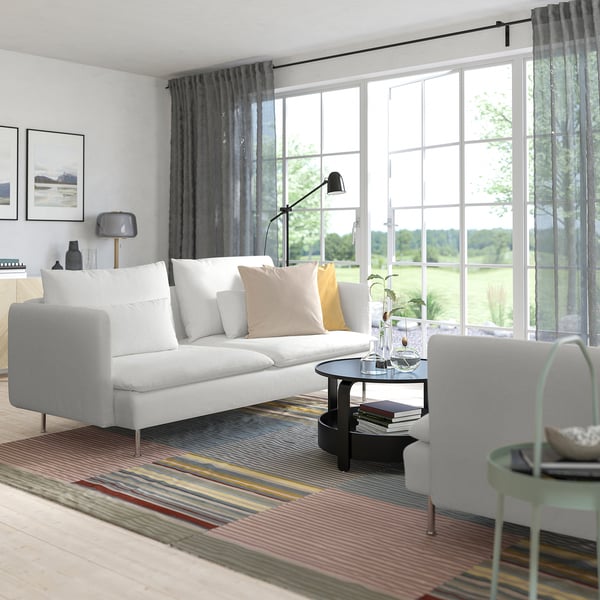 Modern living room with SÖDERHAMN sofa, colourful decor, plant, and window view.