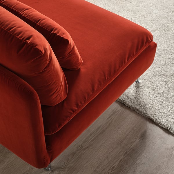 Bright red velvet sofa, plush and inviting, on light wooden floor near beige carpet.