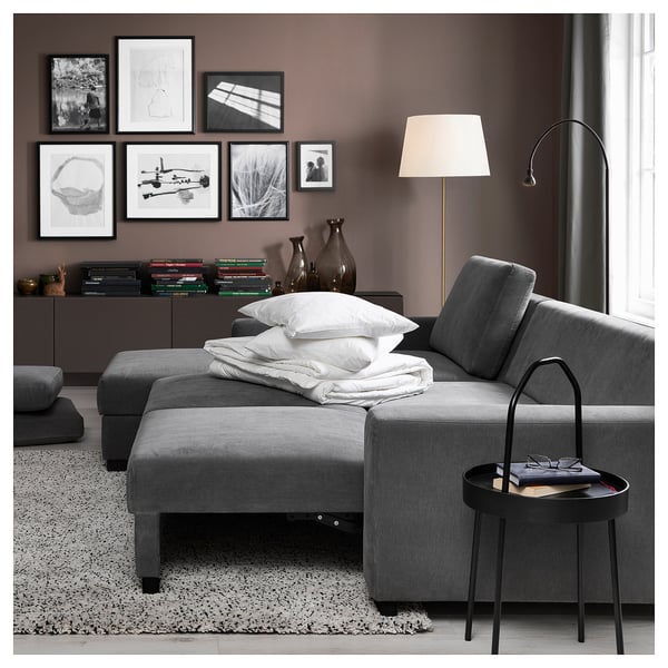 Modern living room with grey SÖRVALLEN sofa, white pillows, black side table, and wall art.