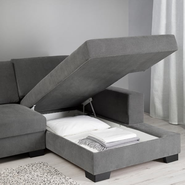 Sofa with lift-up chaise longue for extra storage. Modern, minimalist design with soft cushions and white sheets inside. Grey fabric, lightweight.