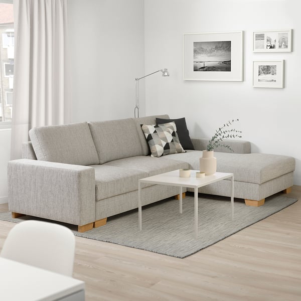 Grey SÖRVALLEN sectional sofa with chaise, patterned cushions, coffee table, black & white art.