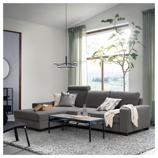 Modern living room with SÖRVALLEN grey sectional sofa, coffee table, large window, curtains, plant.