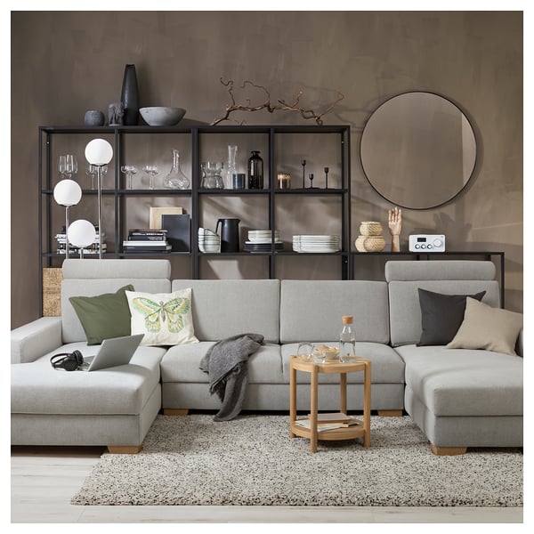 Modern living room with grey sectional sofa, butterfly pillows, wooden table, and bookshelf.