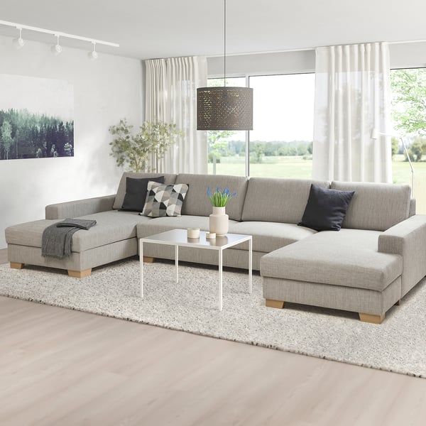 Modern minimalist living room with a large l-shaped SÖRVALLEN sofa in grey, featuring a white coffee table and pendant light above.