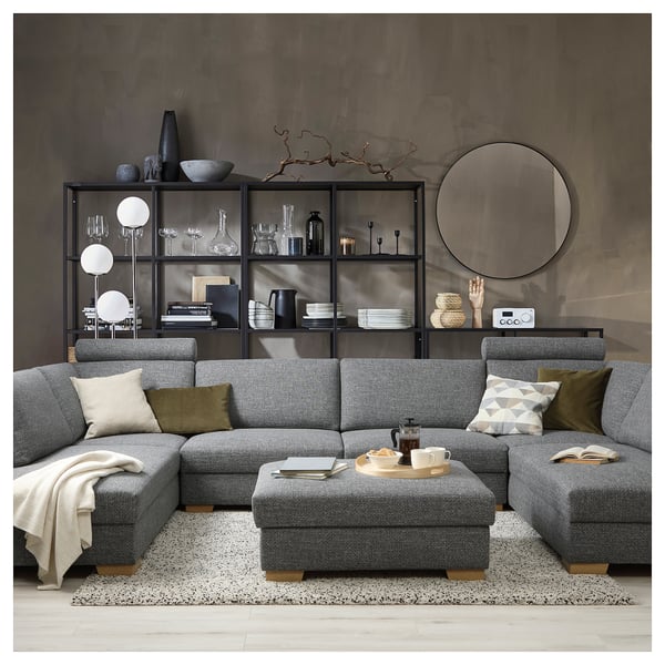 Modern grey sectional sofa, SÖRVALLEN with cushions, chic decor, black shelves, circular mirror on a moody wall.