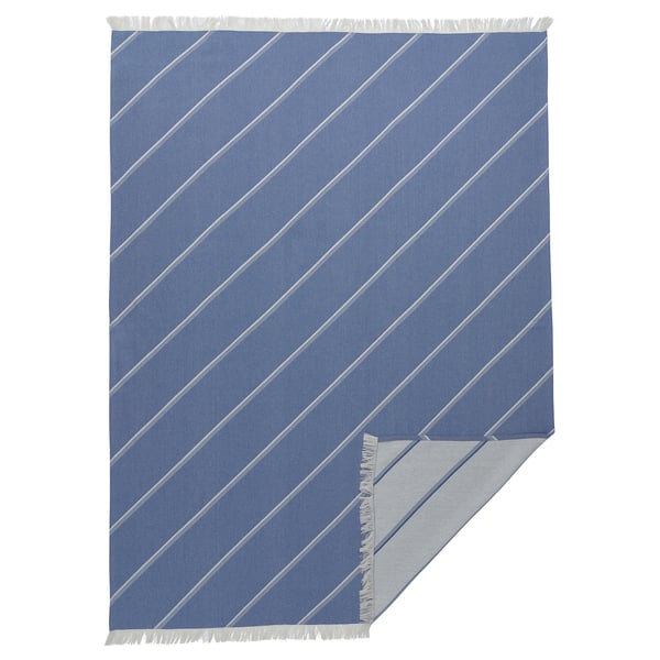 Blue striped blanket with fringes. Modern geometric design. Made of cotton and lyocell. Rectangular shape.
