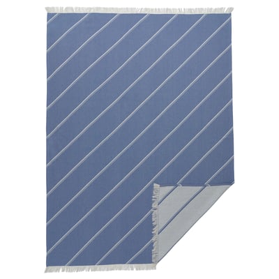 Blue striped blanket with fringes. Modern geometric design. Made of cotton and lyocell. Rectangular shape.