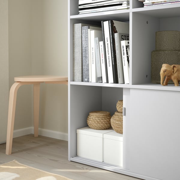 Wooden stool by wall, next to versatile bookcase.