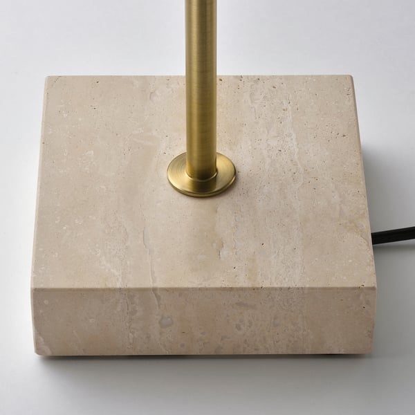 Modern lamp with brass base on travertine stone, elegant and stable.