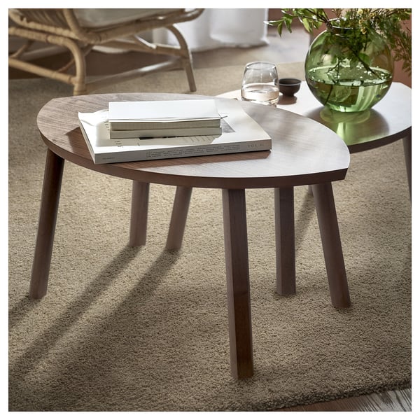 Small round wooden coffee table with books and a green vase on top.