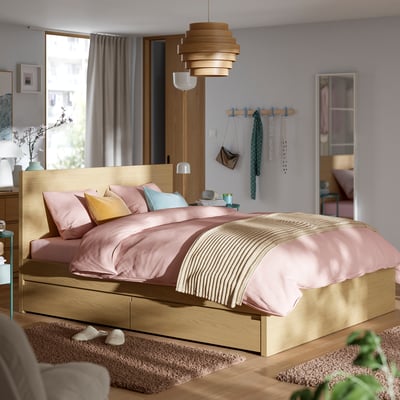 Modern wooden bed, light brown, high headboard, soft pillows, under-bed storage, pendant lamp, mirror, neutral decor.