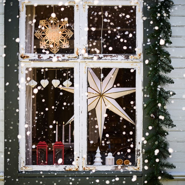Snowflake lamps in christmas window with pine, warm glow, festive.