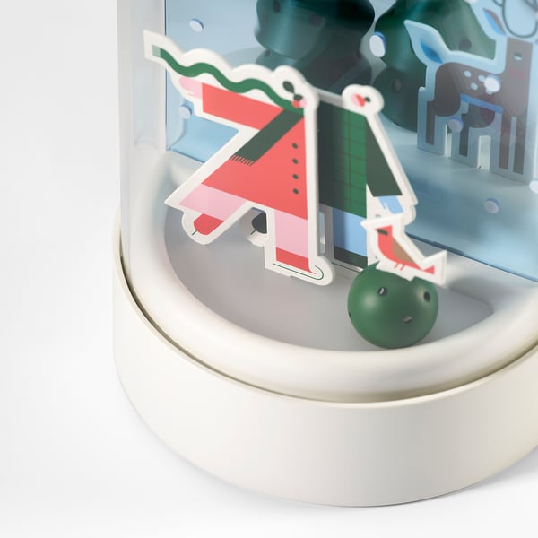 Decorative snow scene light with colourful stove, clear globe, soft light, sits on white base.