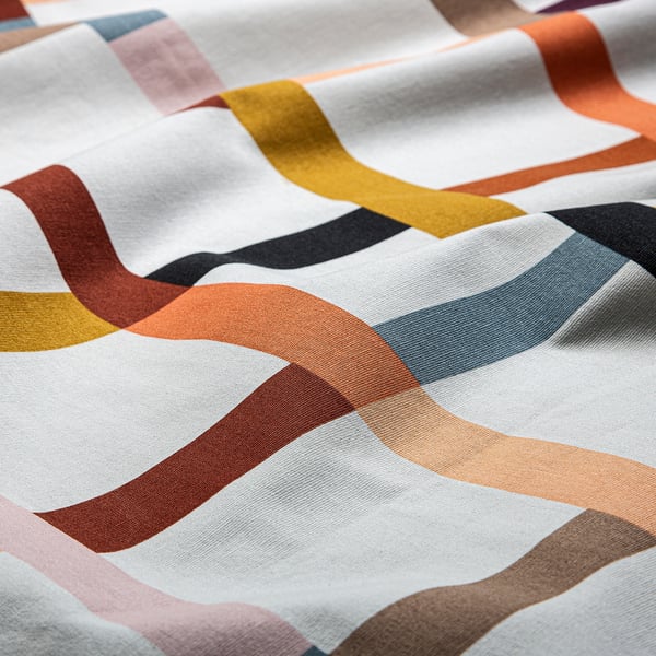 Close-up of colourful, wavy striped fabric on white background; soft, high-quality cotton texture.